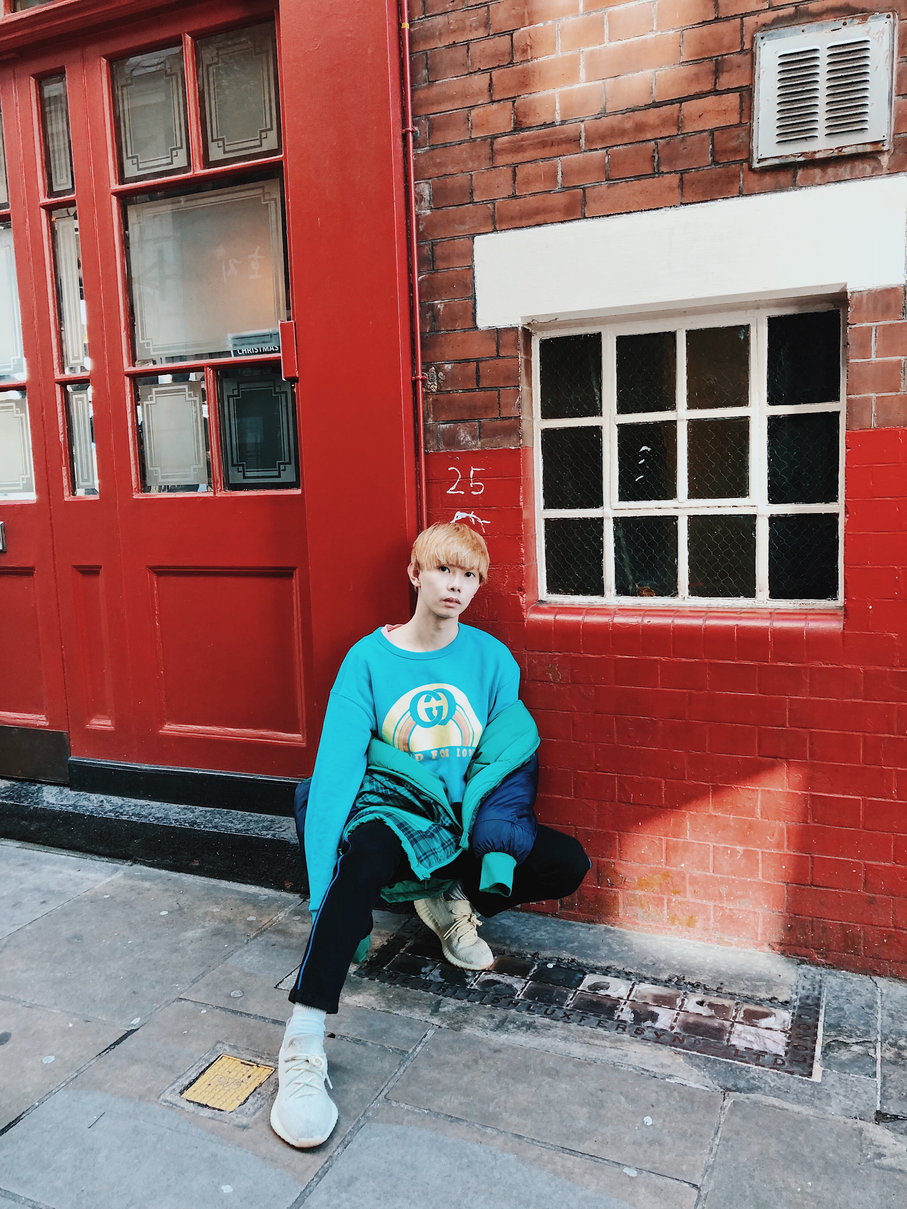 sitting man leaning on red brick wall